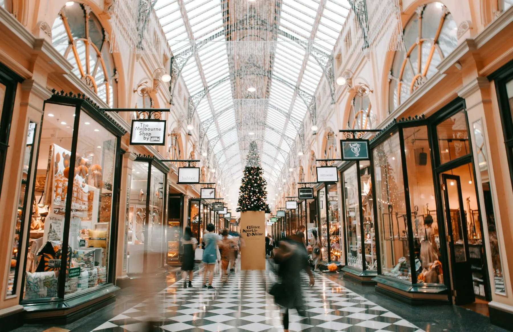 Galería comercial elegante con vitrinas iluminadas y clientes recorriendo el pasillo