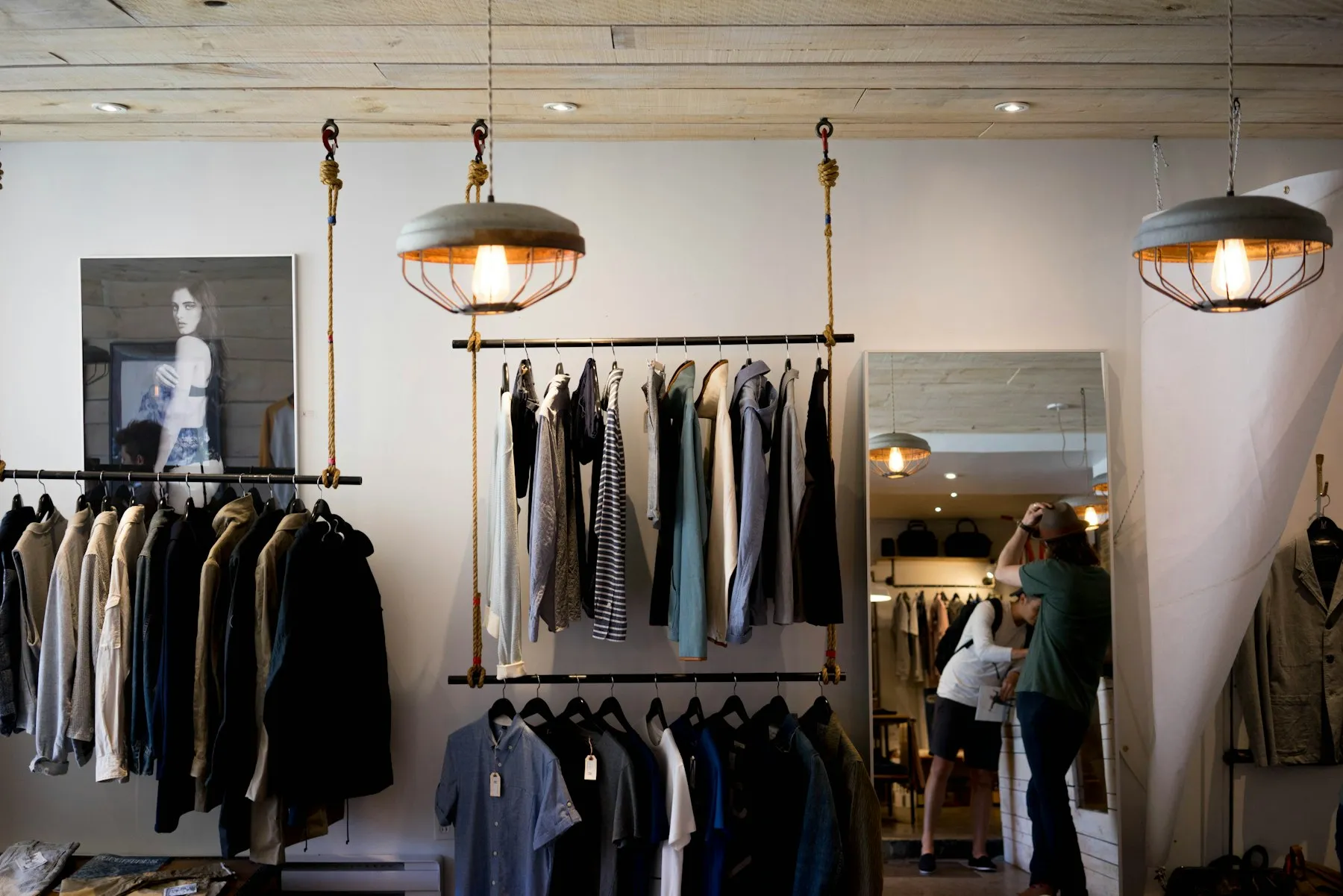 Boutique con prendas colgadas en rieles suspendidos y lámparas de estilo industrial